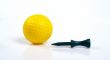 Yellow golfball and green tee with reflecting