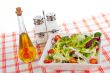 Oil bottle, green salad, salt and pepper