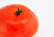 Tomato with water droplets, macro over white