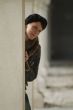 young woman leans at a pillar