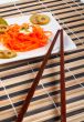 Salad of carrot on a porcelain plate with sticks