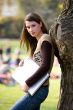 leaning against a tree with notebook