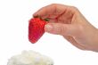 Woman hand strawberry over cream