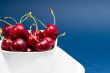 multiple cherries in a white bowl