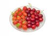 Strawberries and cherries on glass dish, isolated