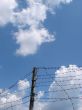 Cloudy blue sky with rugged wire fence