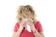 Young blond girl sneezing in the handkerchief