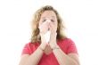 Young blond girl sneezing in the handkerchief