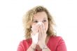 Young blond girl sneezing in the handkerchief