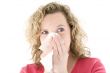 Young blond girl sneezing in the handkerchief