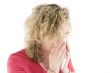 Young blond girl sneezing in the handkerchief