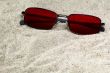 red sunglasses lost in beach sand