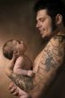 The baby on hands at the man with a tattoo