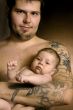 The baby on hands at the man with a tattoo