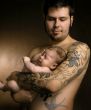 The baby on hands at the man with a tattoo