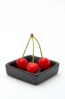 Three cherries in a black bowl