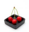 Three cherries in a black bowl