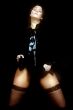 a woman in stockings against a black background