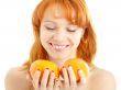 cheerful redhead holding two oranges over white