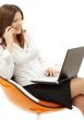 businesswoman with laptop and phone in orange chair