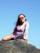 The sexual girl sits on a stone