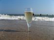 Glass of a cold champagne in warm sea waves