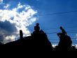 shapes of two people seated on a rock in the sky