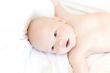 Funny little baby on white bed. View from above