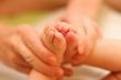 Mother gently hold baby leg in hand