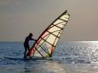 A women is learning windsurfing at the sunset