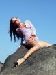 The sexual girl sits on a stone