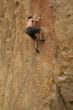 Bare back climber clinging to rock face