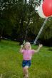 girl with balloon runs on lawn