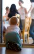 Little baby crawling through door aperture to parents on terrace