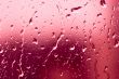 Flowing on transparent red glass water drops