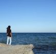 Girl on Rock Looks out to Water
