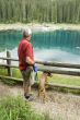 man and dog by blue lake