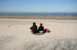 Woman and Man Sitting on Sand Watching Sea in Spring