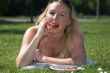 Blond woman eating a strawberry in the park
