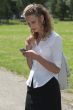 Businesswoman in the park sending a text message