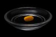 Yellow pill in bright glass saucer isolated on black