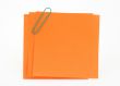 three orange notes with green paperclip