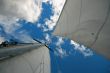 Mast with sails on sky background