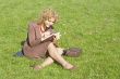 Business women with notebook sits on grass
