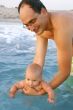 father teachning his baby son to swim