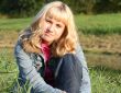 young blond woman is sitting on a grass