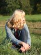 young blond woman is sitting on a grass