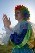 Expressive clown in colored wig upon blue sky