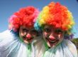 Two bizzare clowns in colored wigs upon blue sky