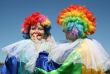 Two bizzare clowns in colored wigs upon blue sky